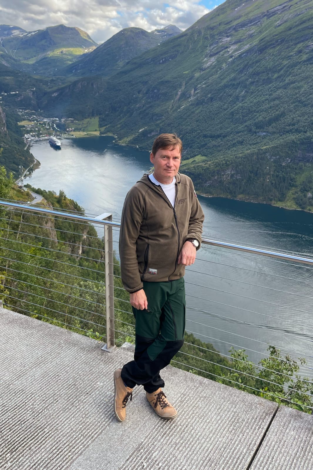 Per-Ola, part of the Saga Tours team, enjoying a bright day outdoors with a clear blue sky and scenic views in the background.