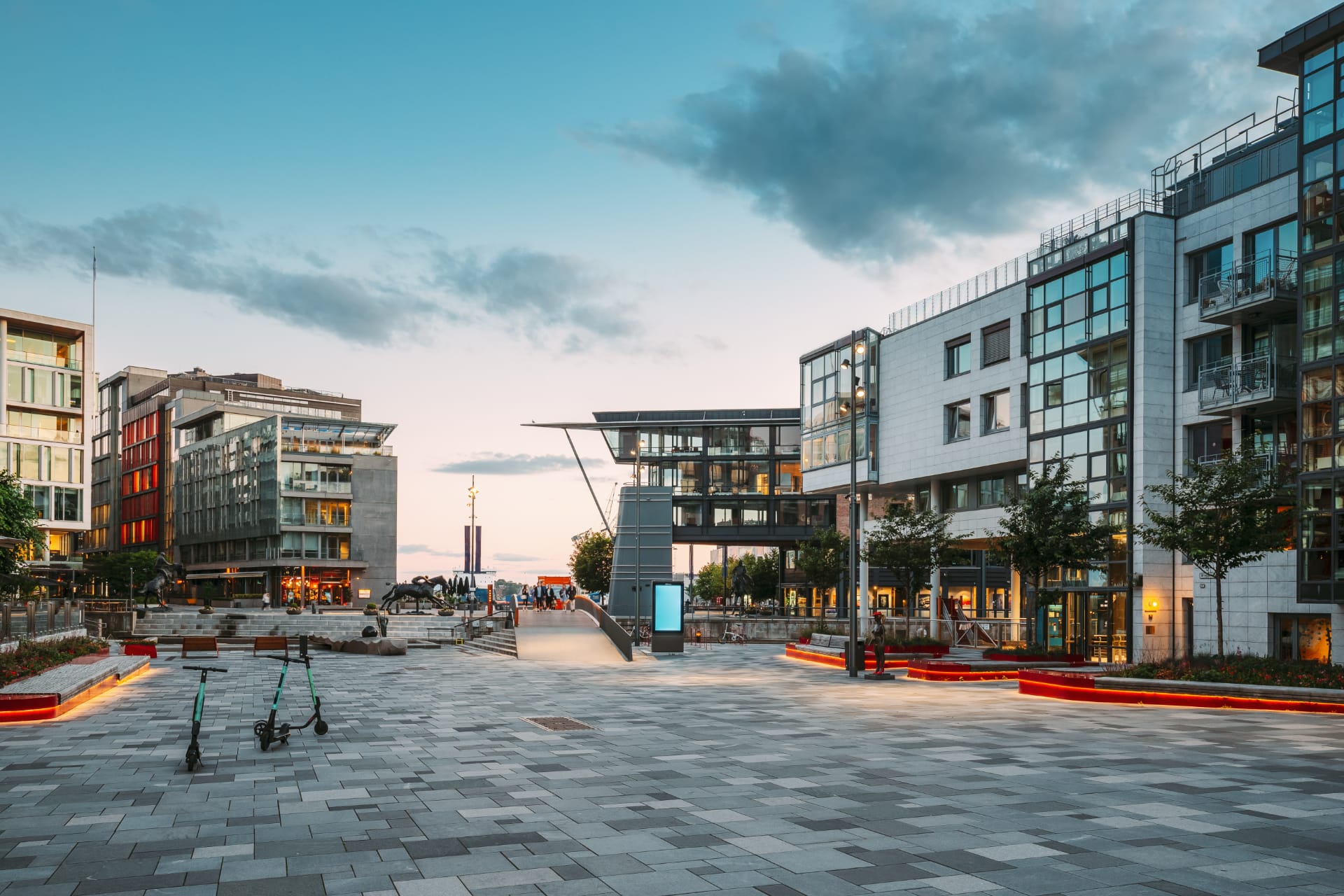 Aker Brygge waterfront district in Oslo, Norway, featuring modern architecture, restaurants, and evening city lights.